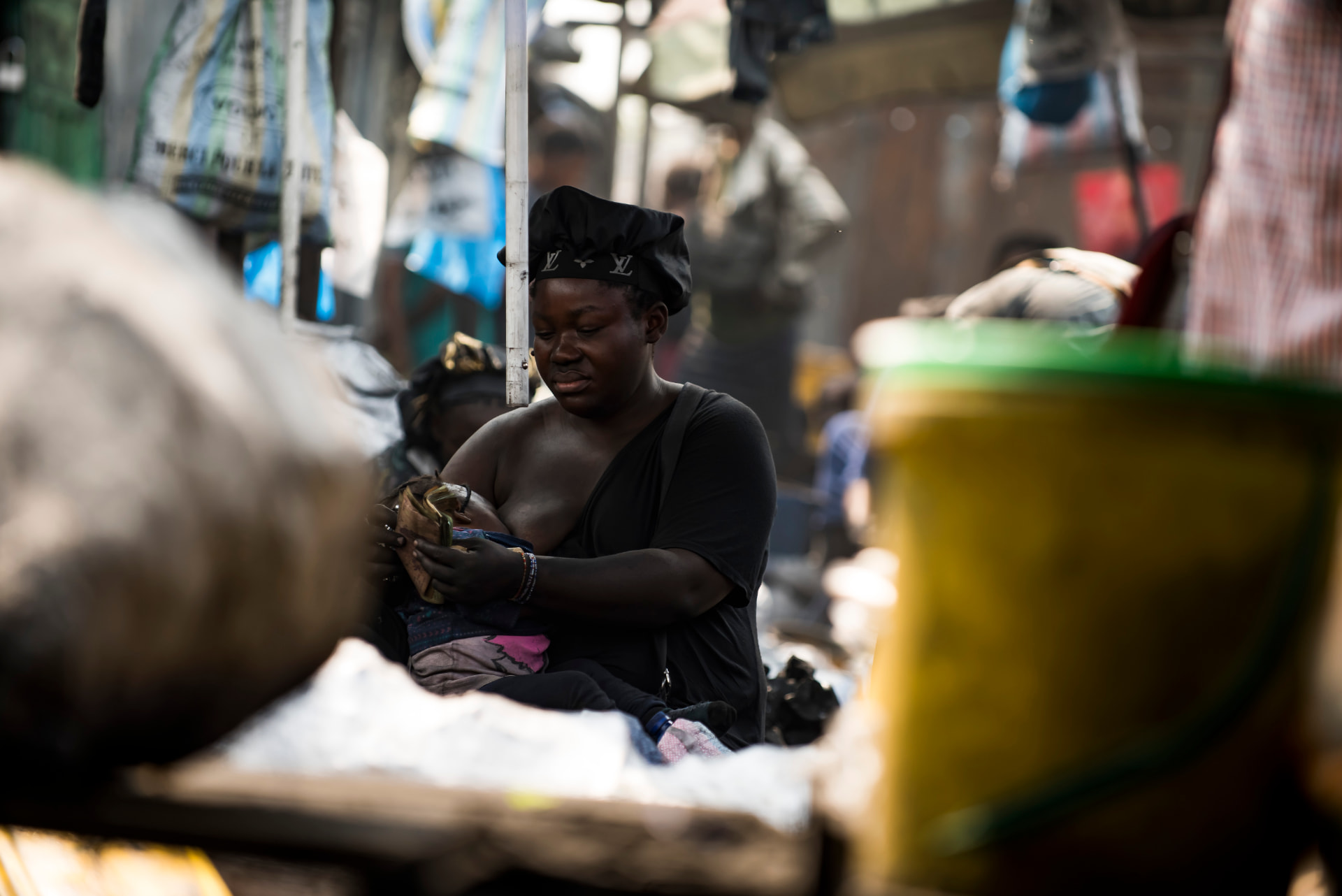 Vendeuse au marché de Kinshasa, coiffée d'un bonnet noir, parmi les étals