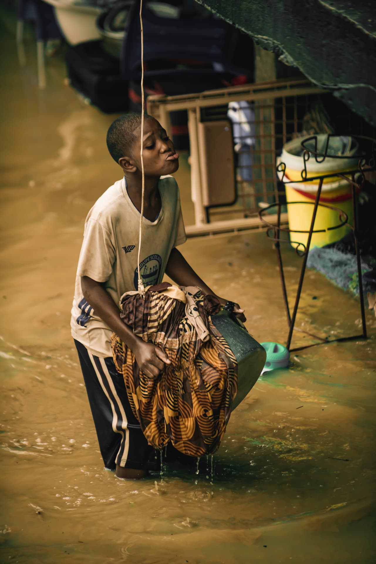 Un enfant rince du linge dans une cour inondée
