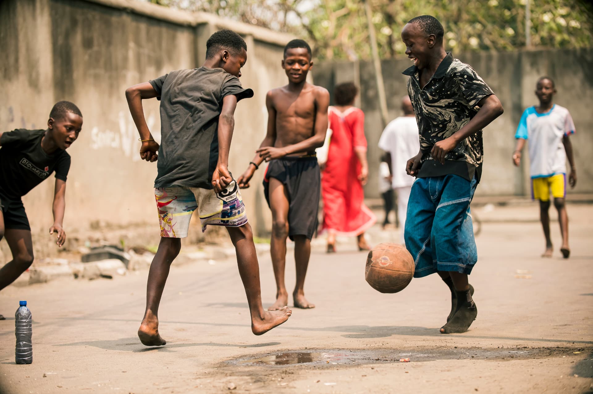 Garçons jouant un match de football improvisé dans une rue de Kinshasa