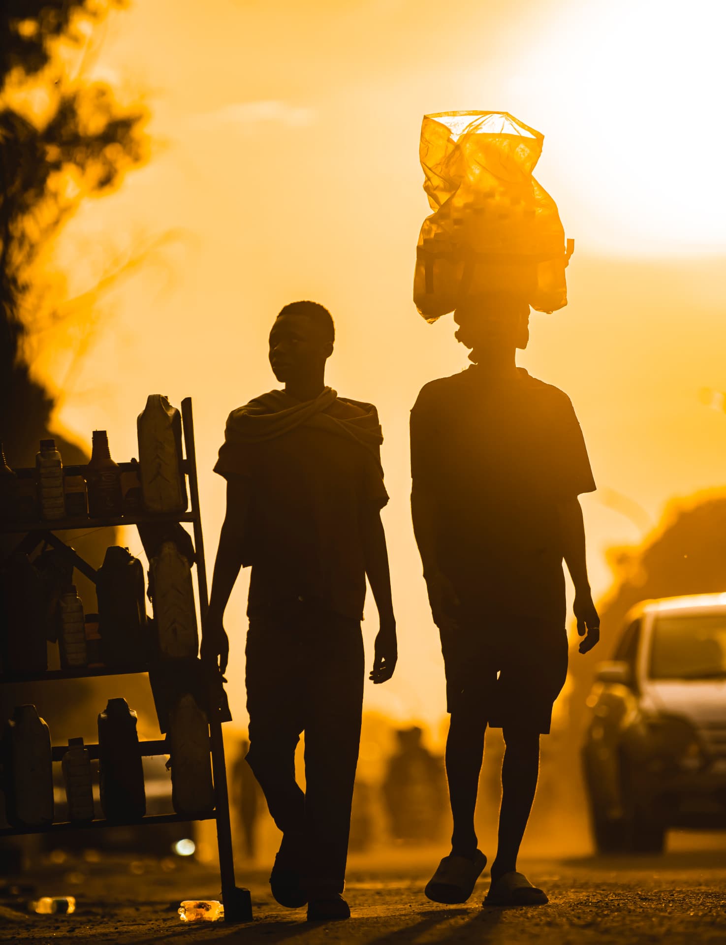 Deux silhouettes marchent à contre-jour au crépuscule, une charge sur la tête