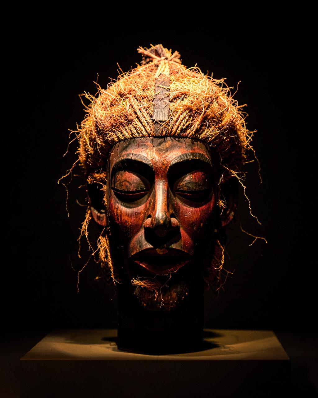 Masque Tshokwe en bois sculpté aux paupières closes, coiffe en fibres